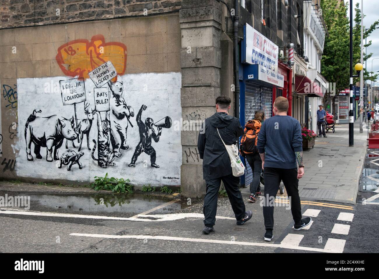 Pedestrians on Leith Walk in Edinburgh walk by a piece of Covid-19 lockdown streetart by The Rebel Bear. Stock Photo