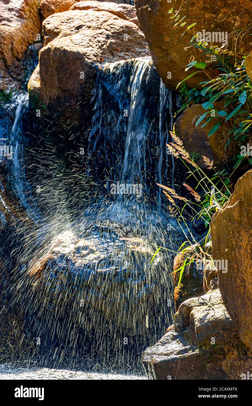 Small Waterfall Between Rocks Small waterfall with waters running and shining between rocks and ...