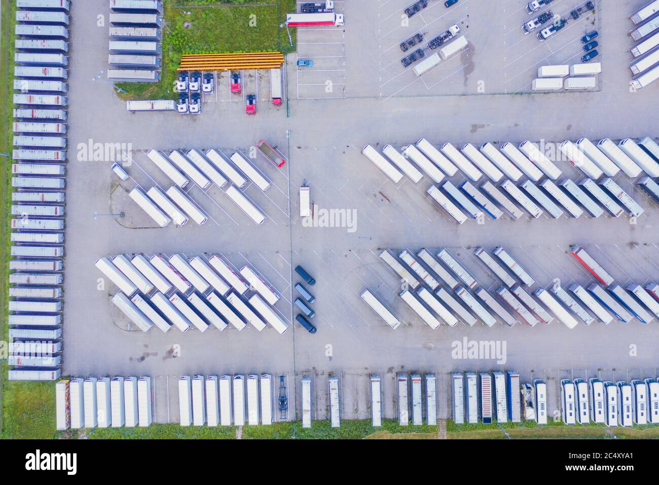 Lots of freight trailers. Cars are in several rows. Truck parking