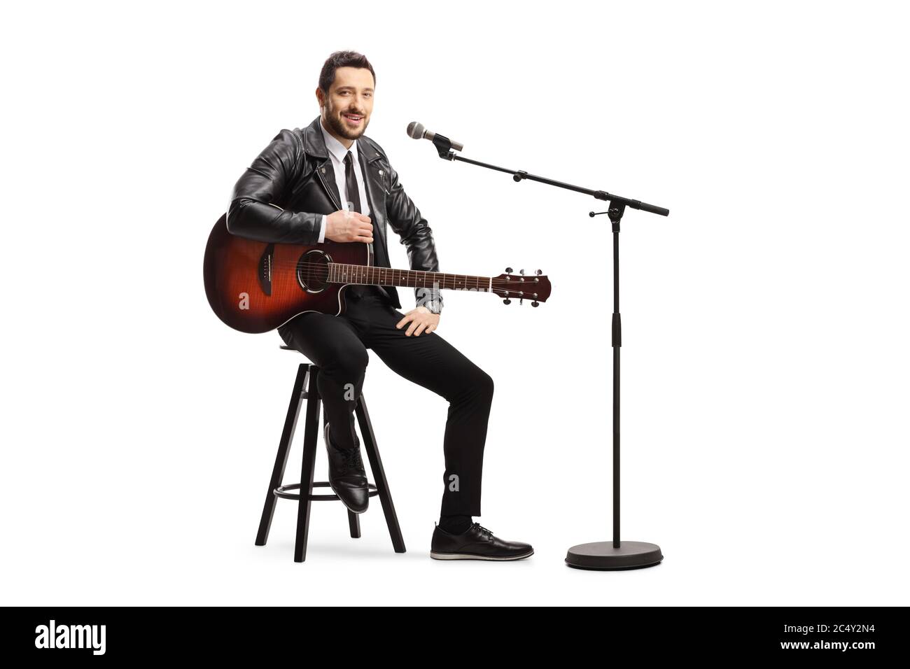 Male singer with an acoustic guitar sitting on a chair with a