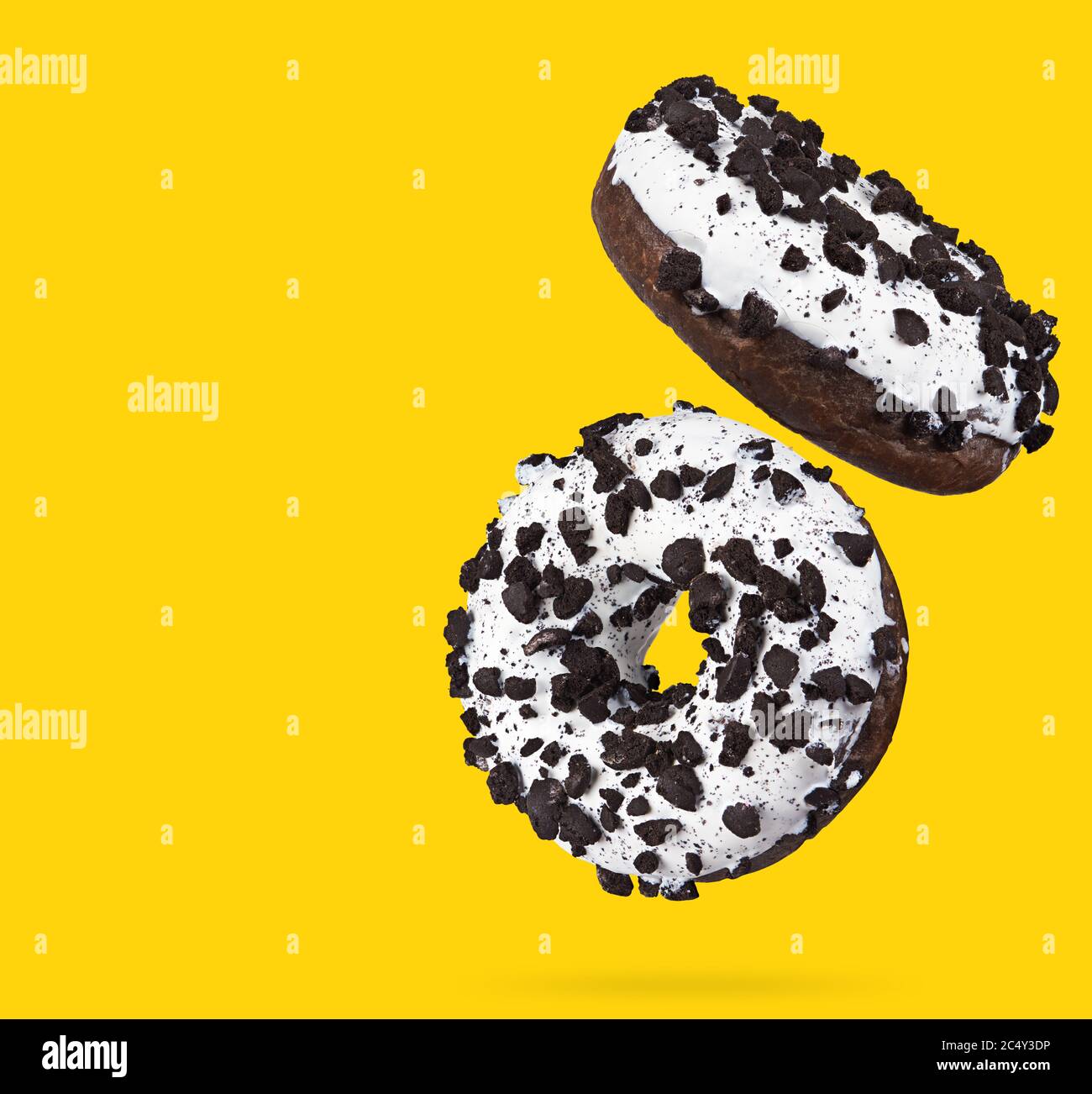 Two chocolate donuts isolated on yellow background. Stock Photo