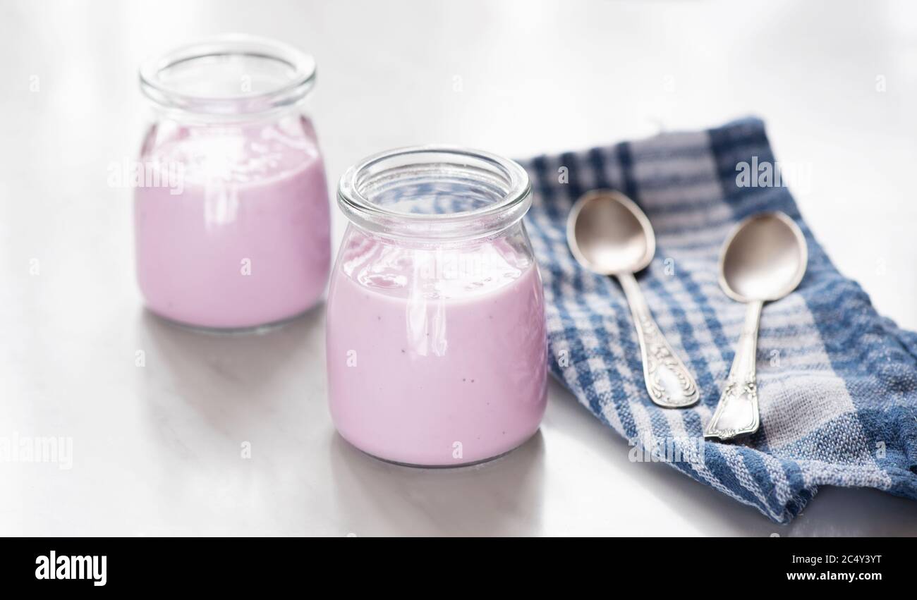 natural homemade strawberry yogurt in a glass jar on a table Stock