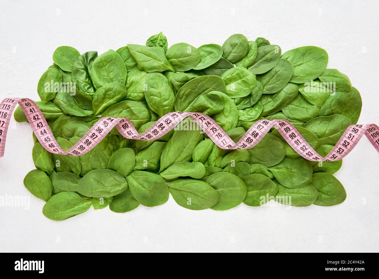 Green spinach leaves with pink tape measure. Healthy food, dietary and