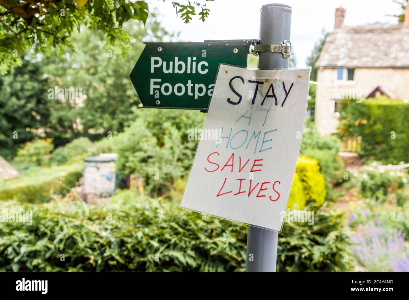 Stay at Home, Save Lives notice tied to a public footpath sign during the Covid 19 pandemic in the Cotswold village of Sapperton, Gloucestershire UK Stock Photo