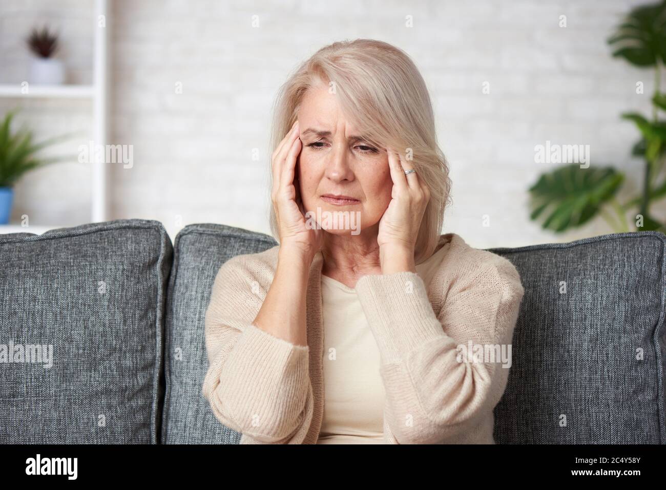 Sad senior woman having headache. Old lady is sick. Stock Photo