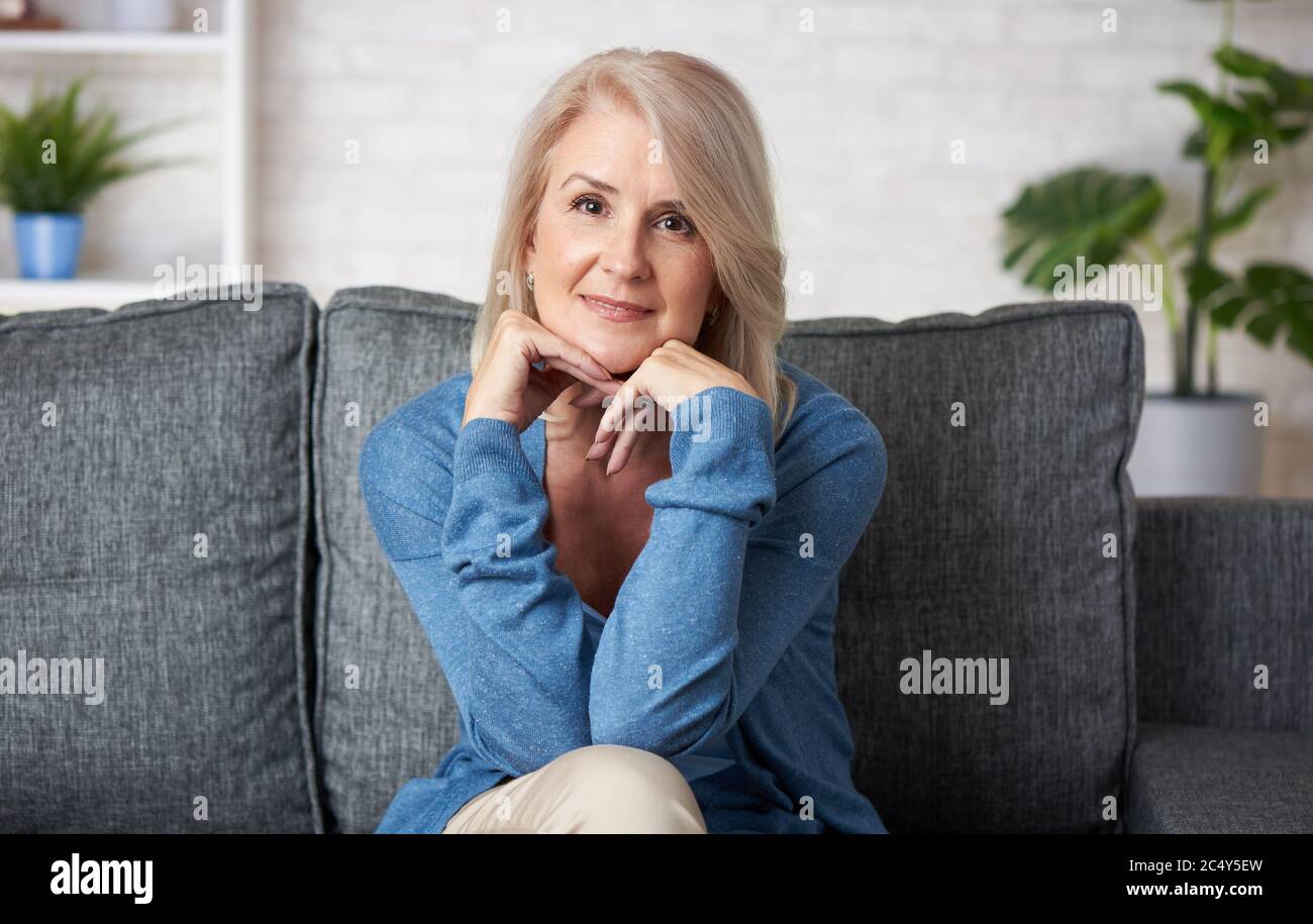 Portrait of senior woman is sitting on a sofa in living room Stock ...