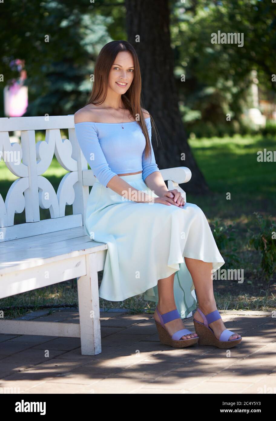 Pretty young woman sitting on bench in park Stock Photo - Alamy