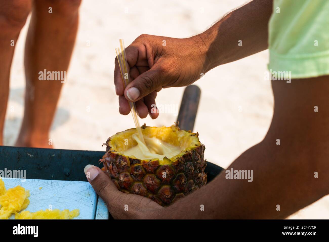A Caribbean local mixes a piÃ±a colada inside a fresh Pineapple Stock Photo