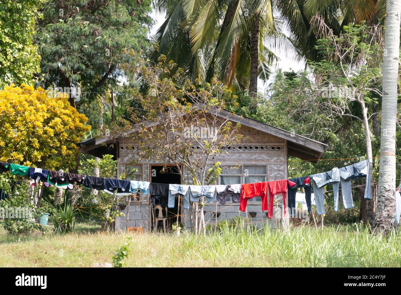Freshly laundered clothes hang before a filipino nipa hut on Samal Isl Stock Photo