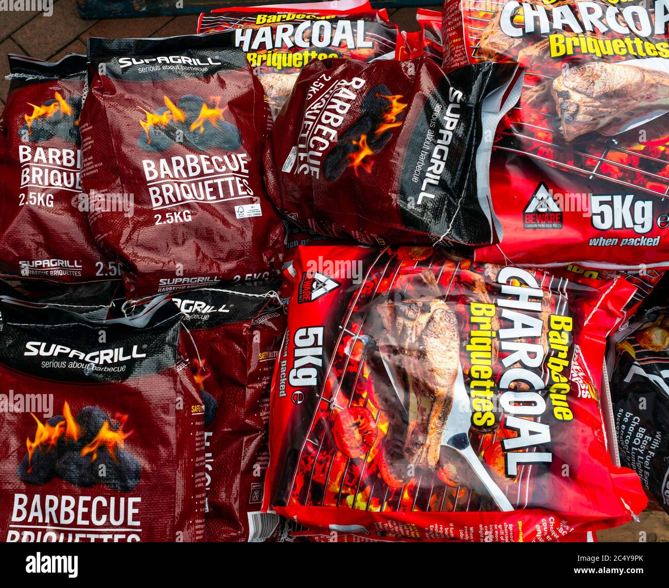 A stack of Instant Lighting charcoal briquettes for barbecue fuel in a  garden centre mixed 2.5Kg and 5Kg sizes Stock Photo - Alamy