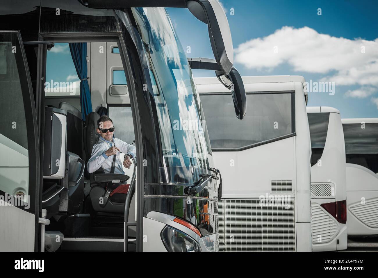 International Coach Bus Driver In Cabin Pointing At Wrist Watch 