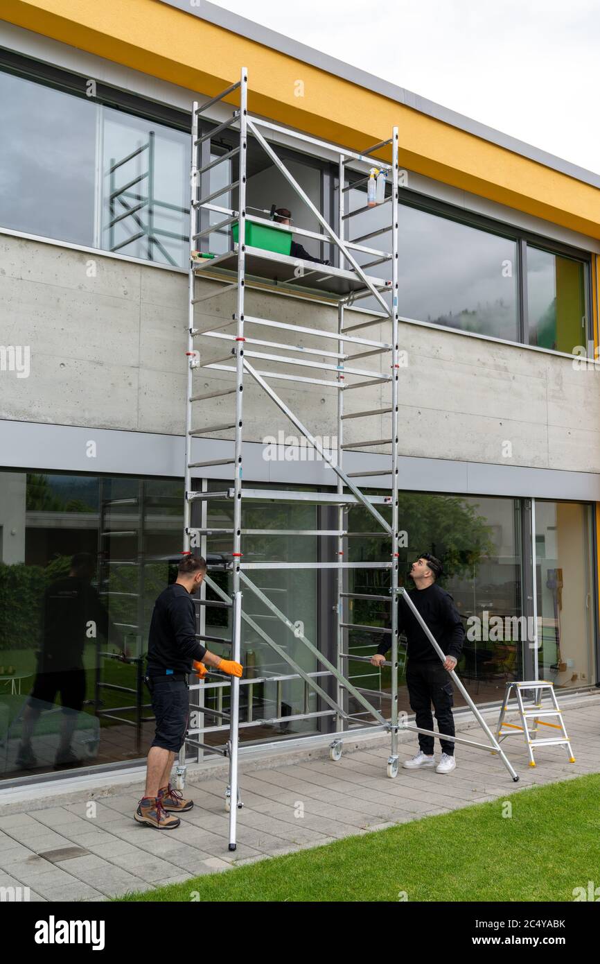 Two professional window washers move a portable scaffolding along a