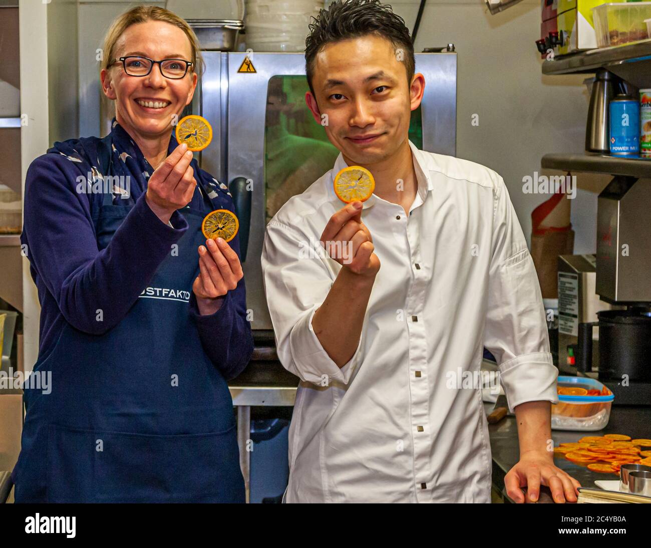Journalist Angela Berg with Souchef Kazunori Tanigawa who presents his wafer-thin orange crackers. Food Tour with Michelin Star Chef Loic Le Bail in Morlaix, France Stock Photo