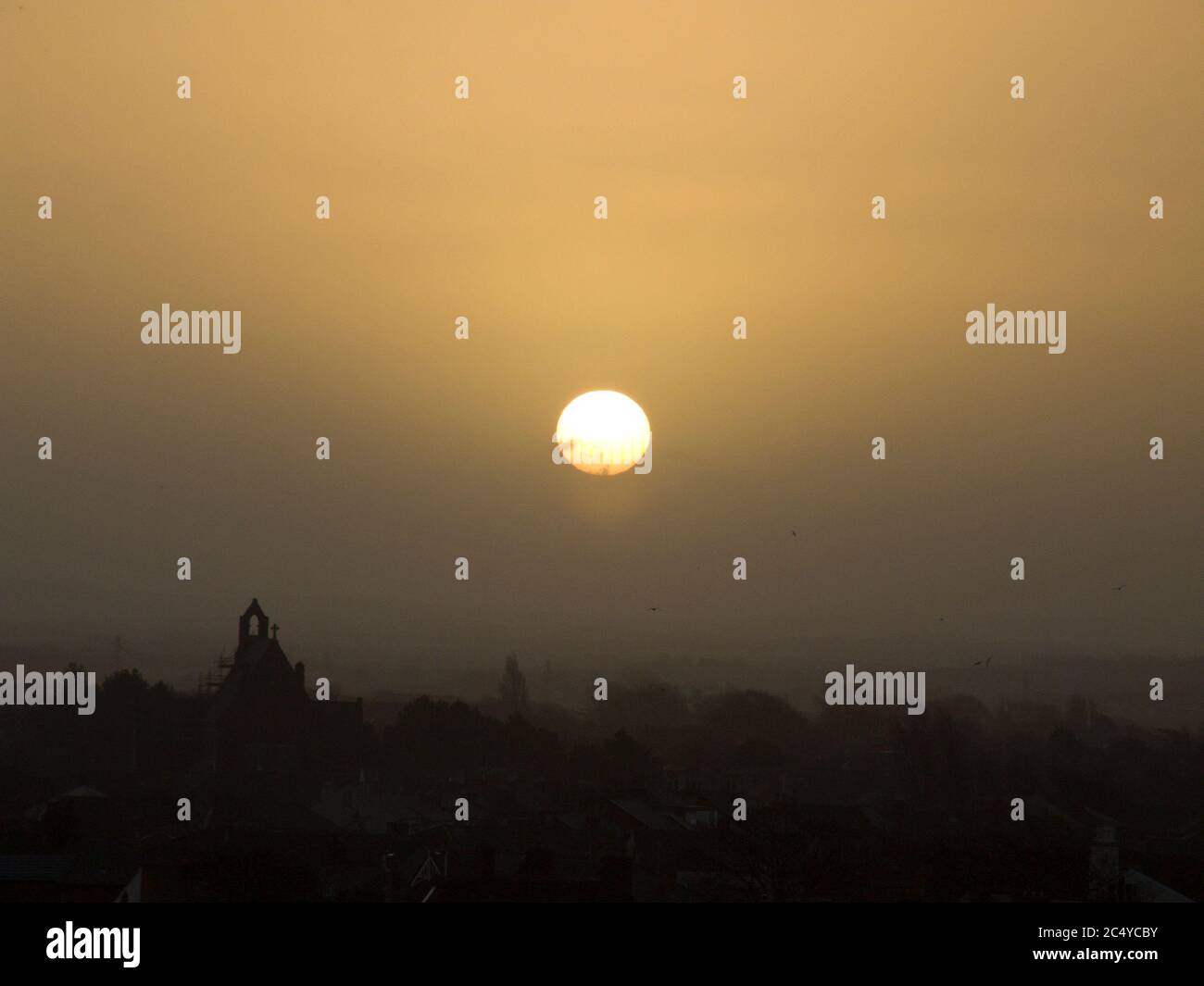 Sun rising over a Spanish, Portuguese or Mexican looking vista. Full disc, church, view, silhouette, sunset, sunrise, unobstructed view Stock Photo