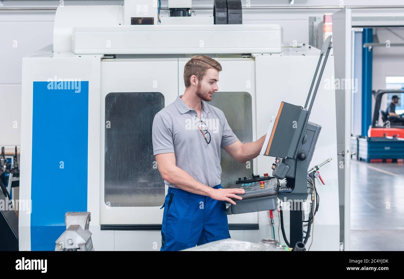 Worker operating computer-controlled machine tool Stock Photo