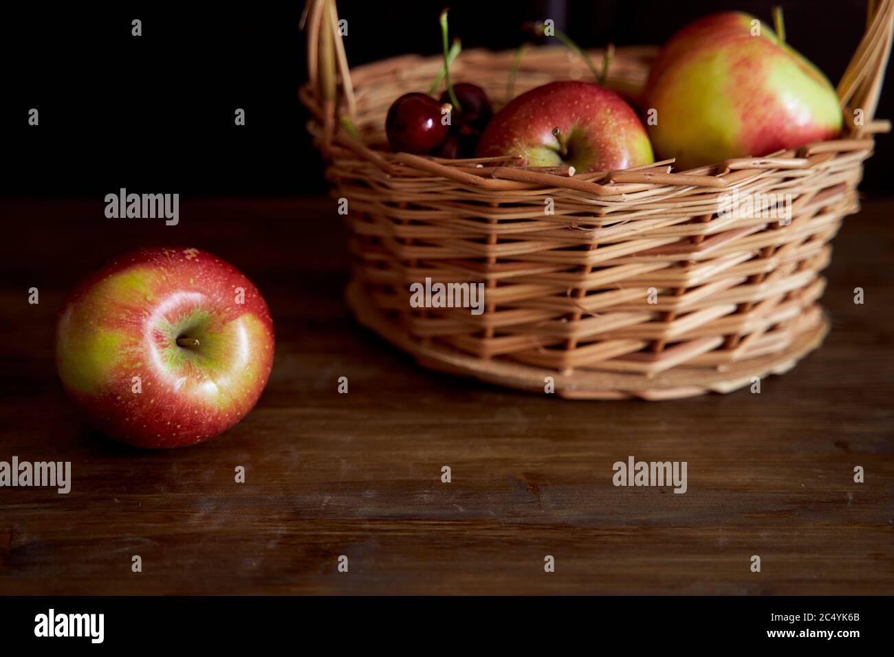 Braided basket with red apples on a black background Stock Photo