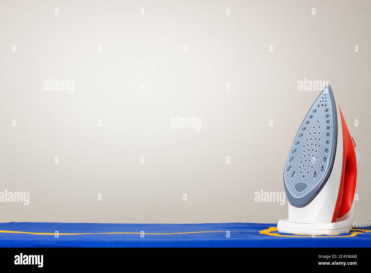Iron on Ironing Board Against a White Wall with Copy Space extreme closeup Stock Photo