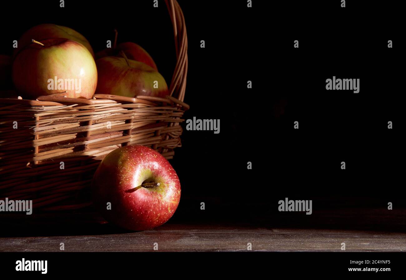 Braided basket with red apples on a black background Stock Photo