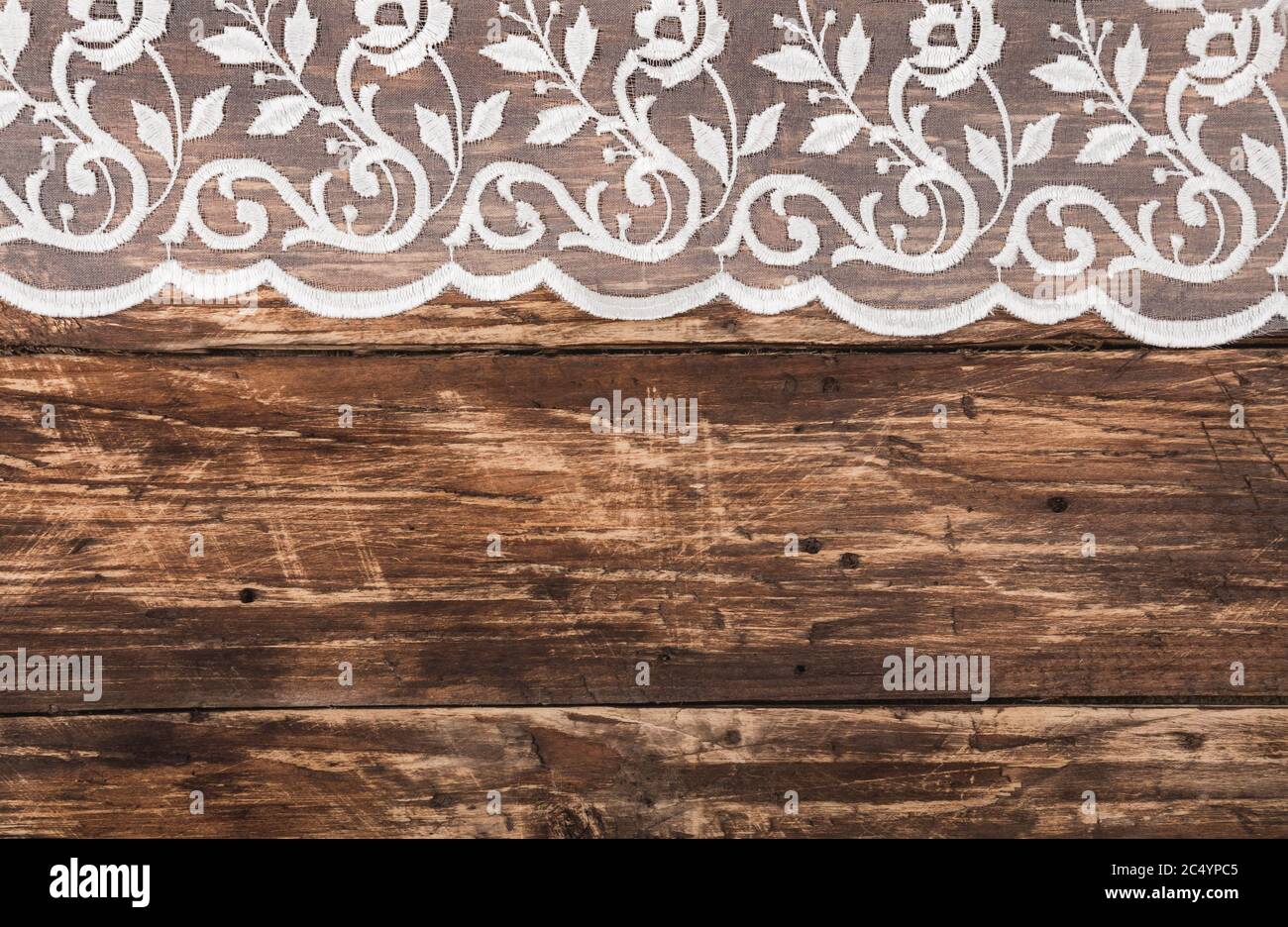 Old grunge rustic dark scratched wood texture background decorated with white vintage guipure lace from above . Text space, empty template. Stock Photo