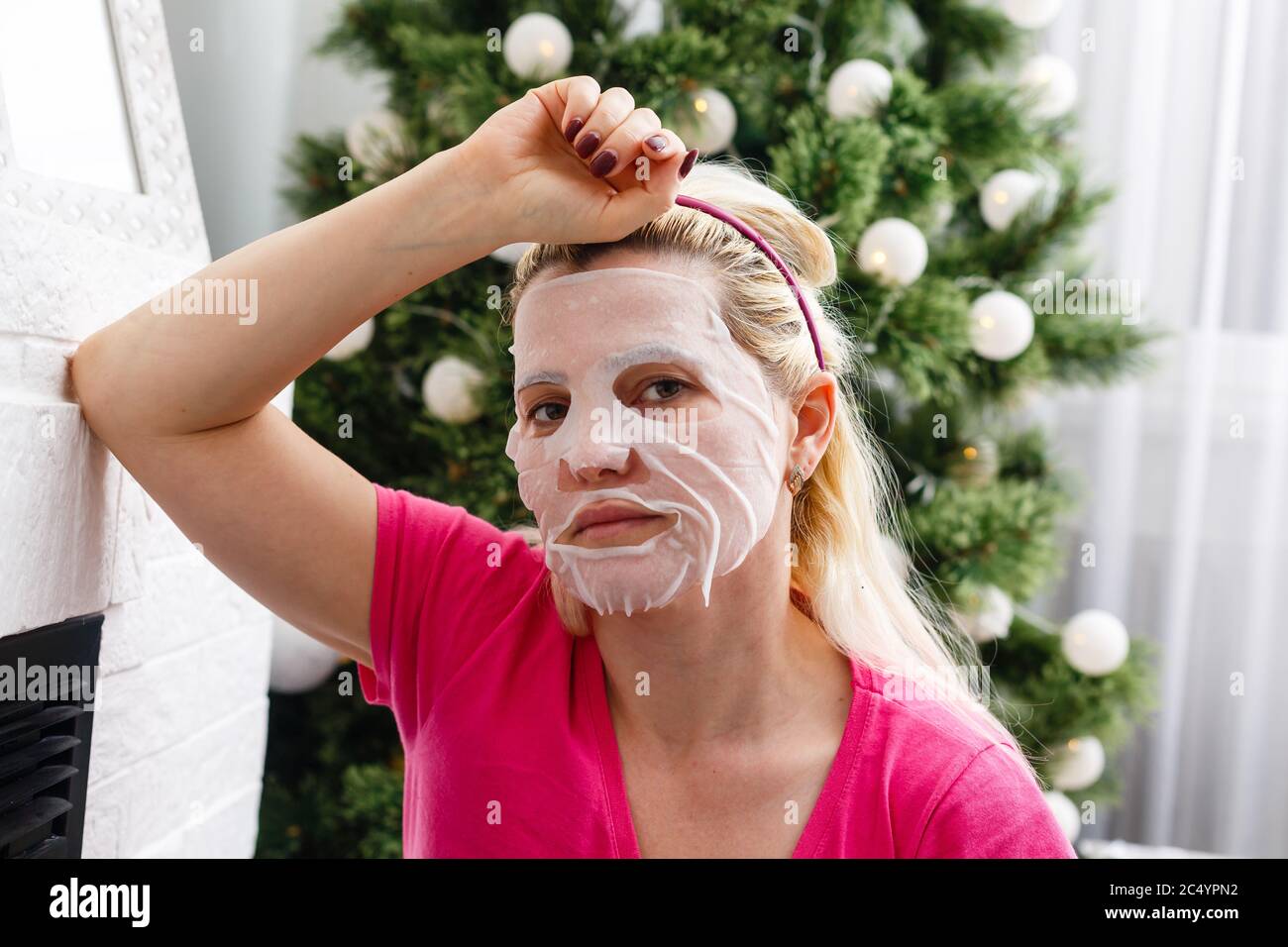 young unhappy girl has headache of christmas stress with tree in