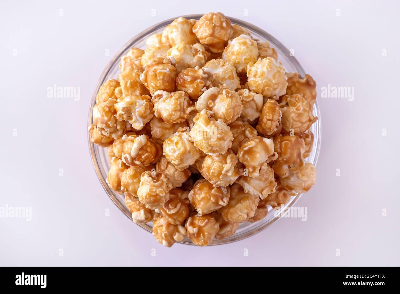 Sweet caramel popcorn in glass bowl. Close up. White background. Top view. Stock Photo
