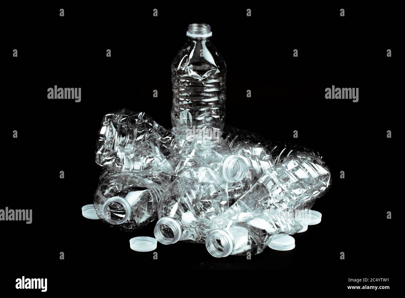 crushed empty clear plastic single use water bottle garbage on a black background Stock Photo