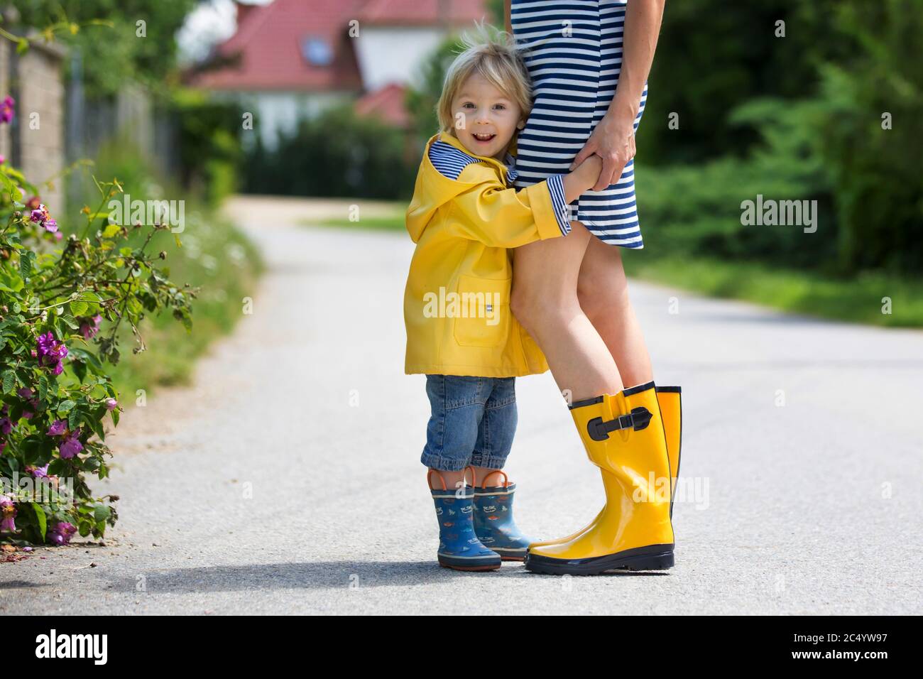 Mother and toddler child, boy, playing in the rain, wearing boots and