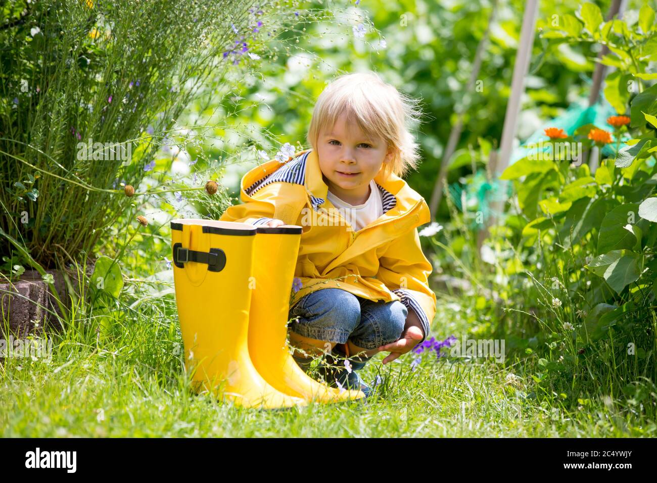 Mother and toddler child, boy, playing in the rain, wearing boots and