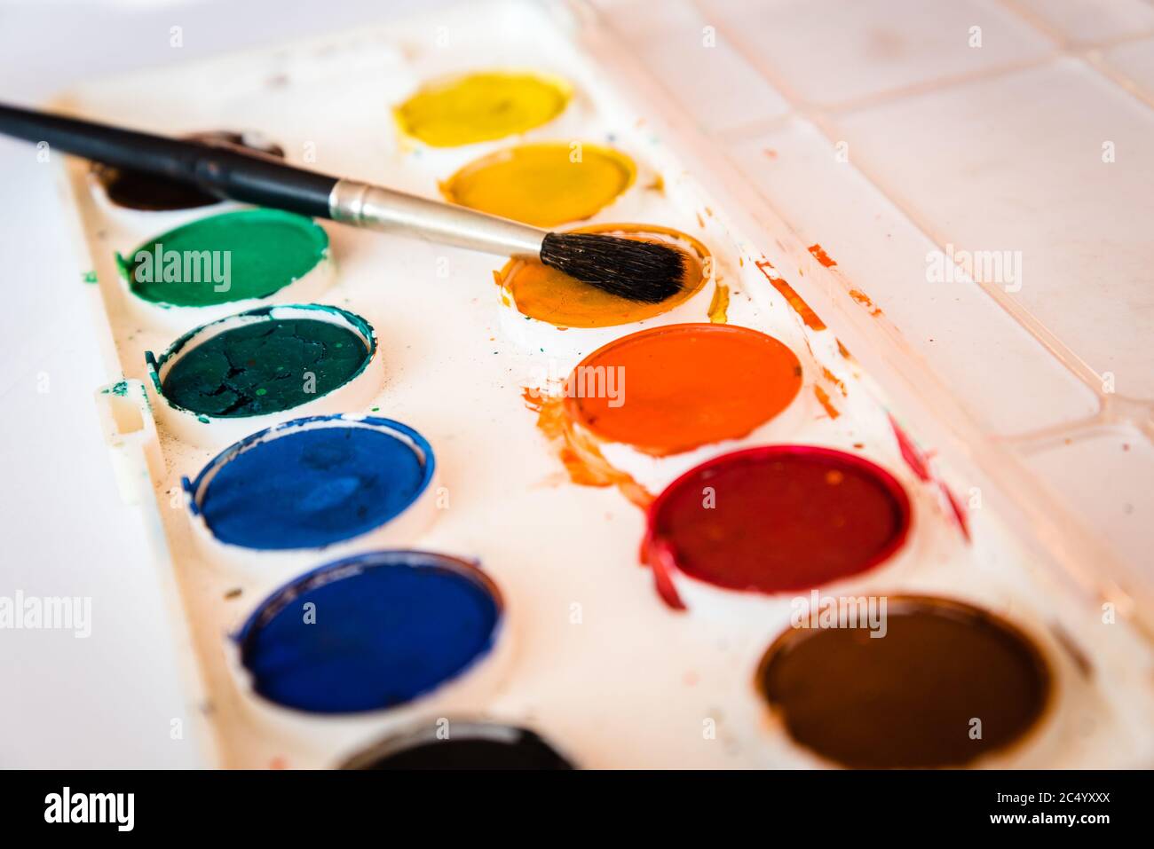 The palette of watercolor paint and one brush on white sheets of paper Stock Photo