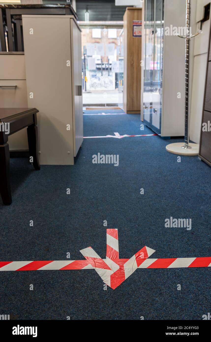 Directional markings on the floor of a furniture shop as required by government rules of social distancing for retailers. Stock Photo