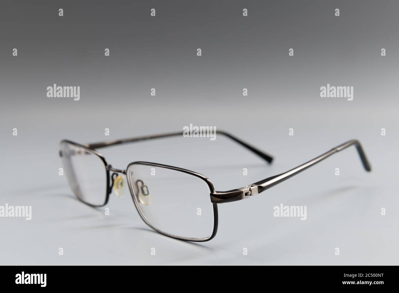A pair of metal frame prescription eye glasses isolated with a grey background. Stock Photo