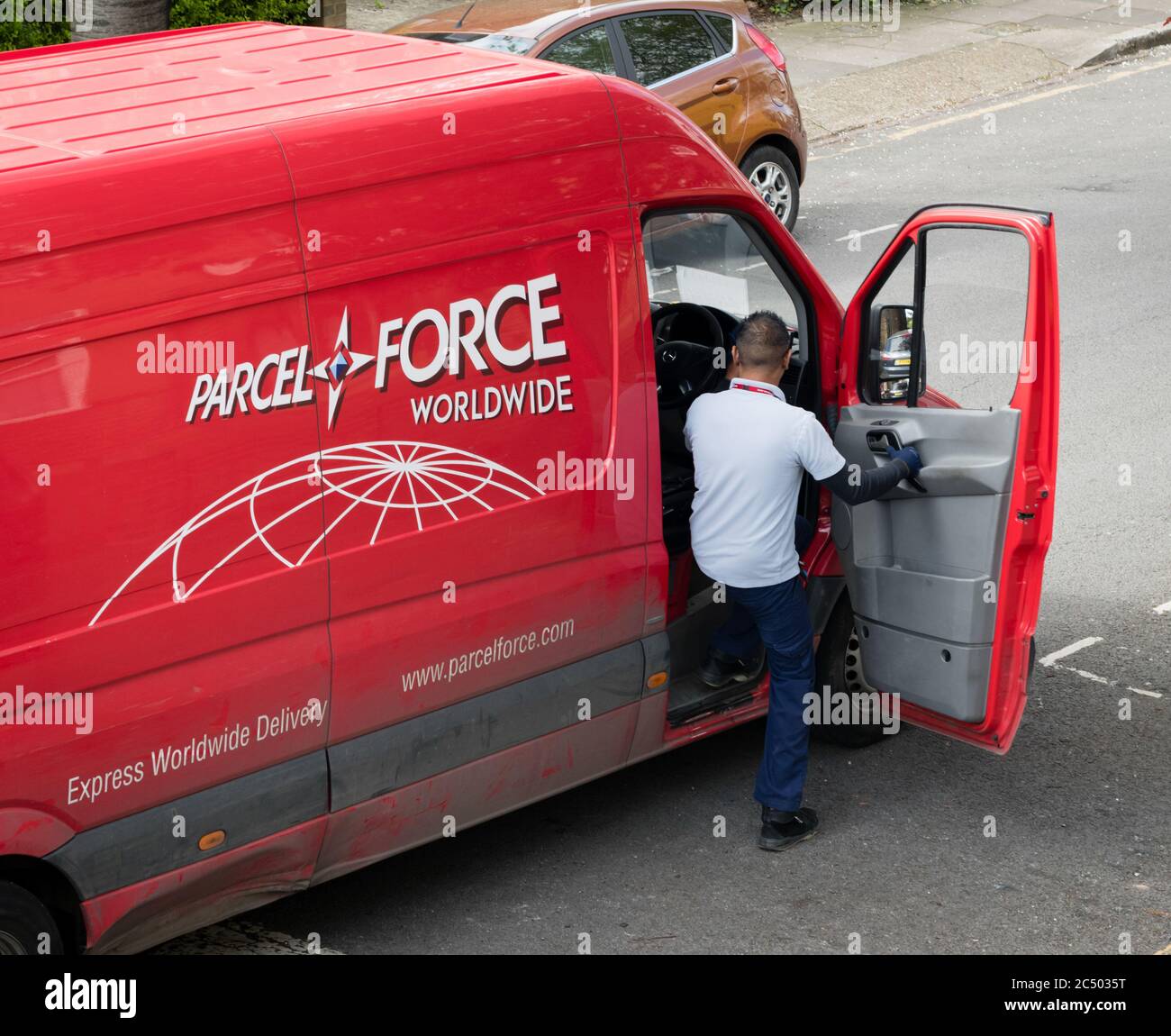 A delivery driver for the logistic company Parcel Force which is part of Royal Mail getting into the delivery van after making a delivery. Stock Photo