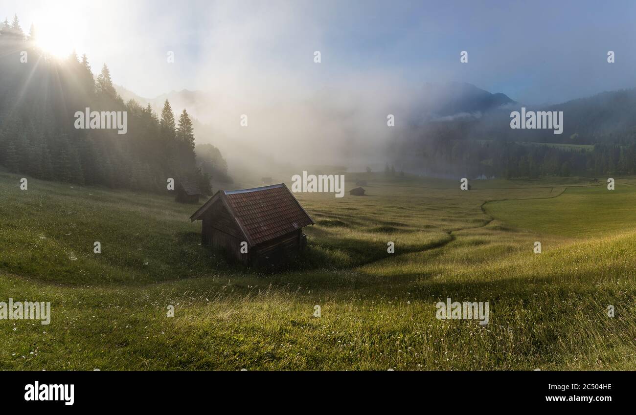 Panorama of foggy morning in the mountains - meadow and hut near Lake Gerold Stock Photo