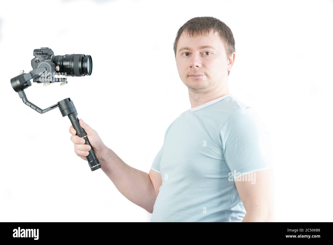 The guy holds a 3-axis stabilizer with a camera in his hand, takes a selfie video. Stock Photo