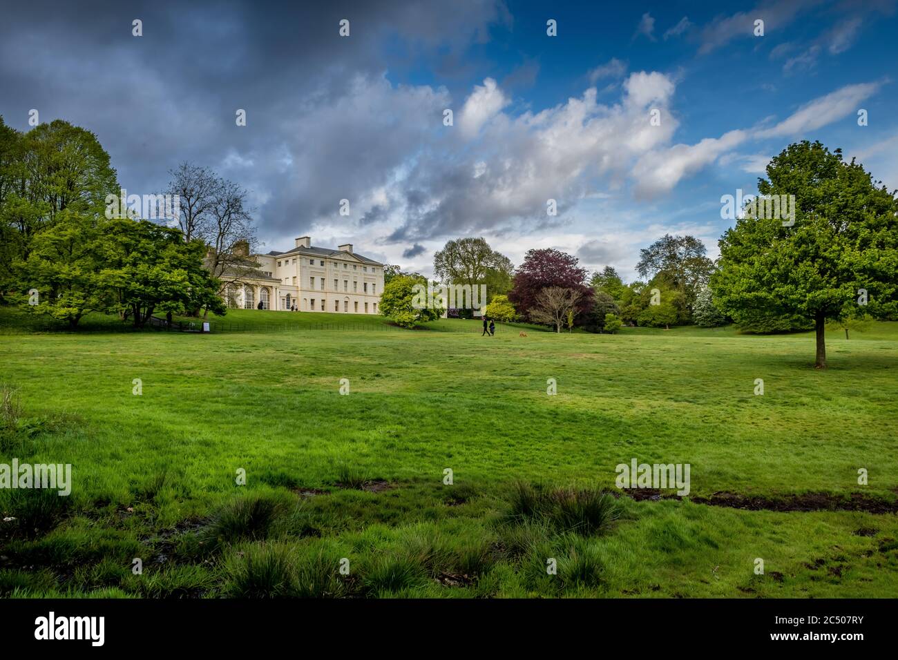 Kenwood House and the surrounding grounds in Spring time with lush green grass and trees on a beautiful day with blue sky clouds. Stock Photo