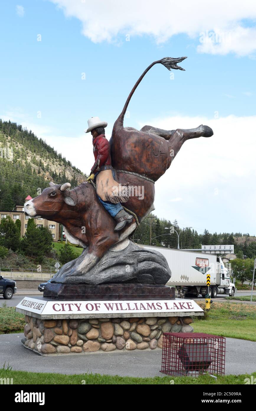 A wooden statue of an indeigenous cowboy riding a rodeo bull sits near the highway in Williams Lake, British Columbia, Canada in the Cariboo-Chilcotin Stock Photo