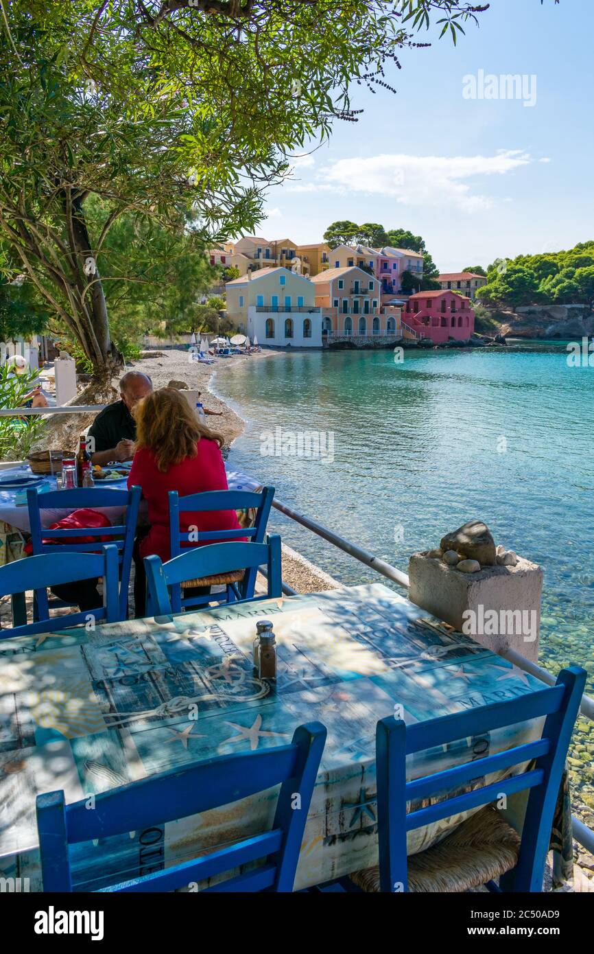 A restaurant with tables next to the sea in the village of Asos, Kefalonian, Greece, offering a wonderful dinning experiance with beautiful views. Stock Photo