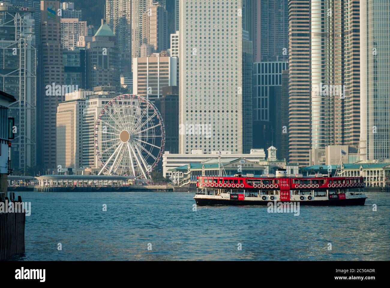 A Star Ferry boat in Hong Kong harbour crossing the seafront of Central District with its many sky scrapers. Stock Photo