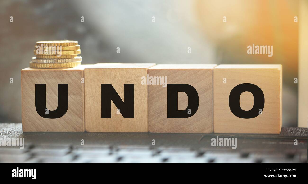 Undo word on wooden cubes with letters, and stack of coins. Technical issue computer program concept. Lifestyle and state of mind concept Stock Photo