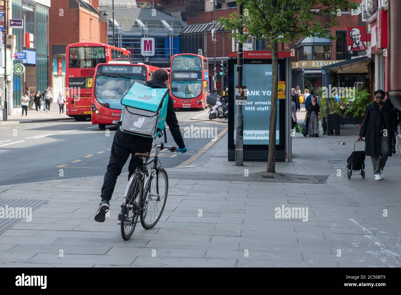 A cyclist working for Deliveroo home delivery service in a London high street. Stock Photo
