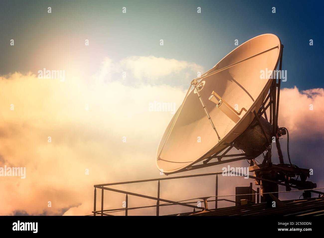 Parabolic tv antenna dish against sky with sunlight with copy space. Stock Photo