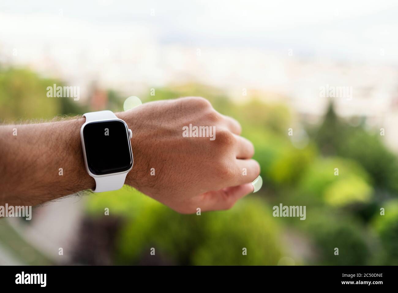 Izmir, Turkey - June 11, 2020: Close up shot of Apple brand 5th generation white colored Apple watch on a mans wrist and defocused green background. Stock Photo