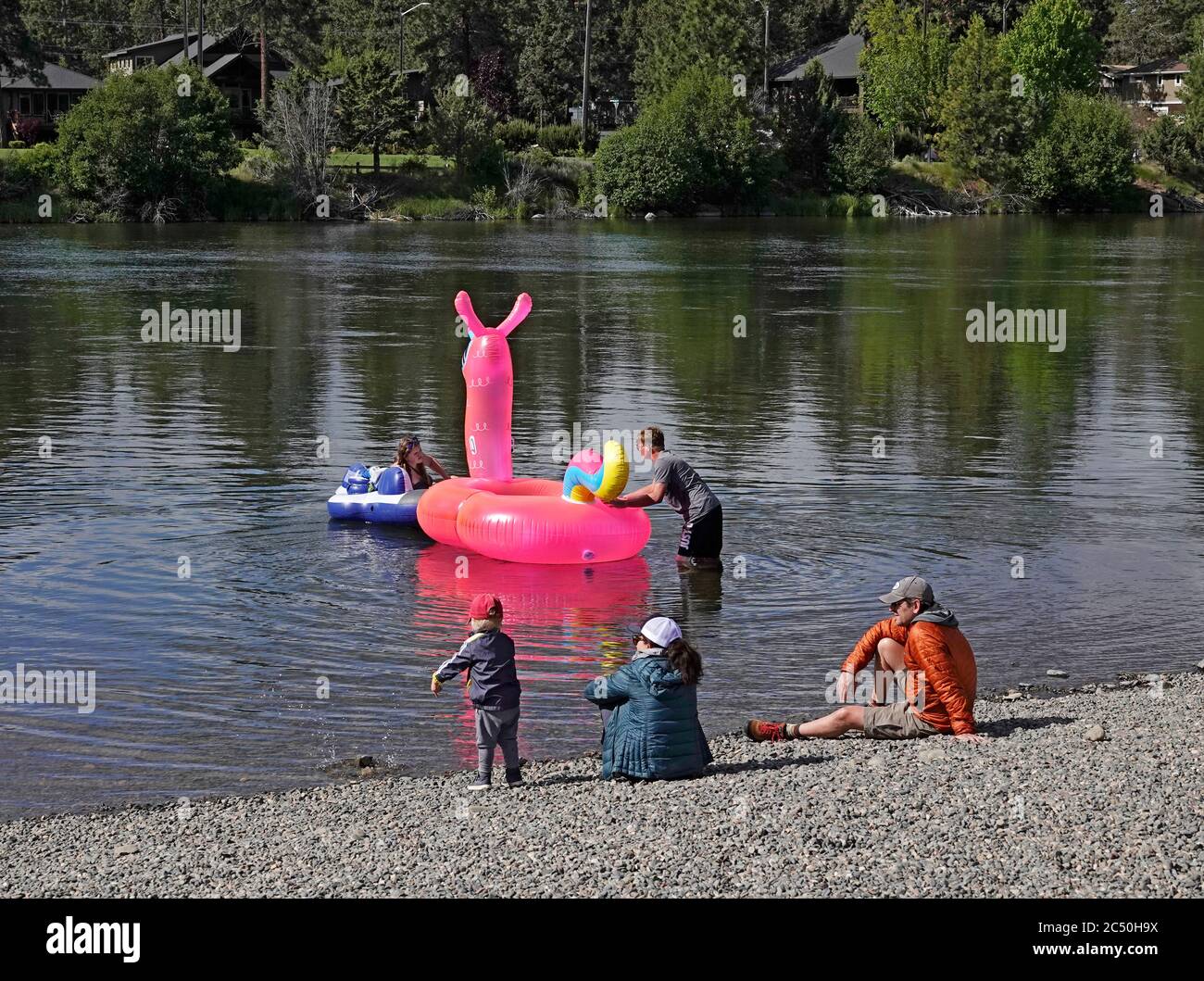 A family with a dog floating the Deschutes River in floating tubes near