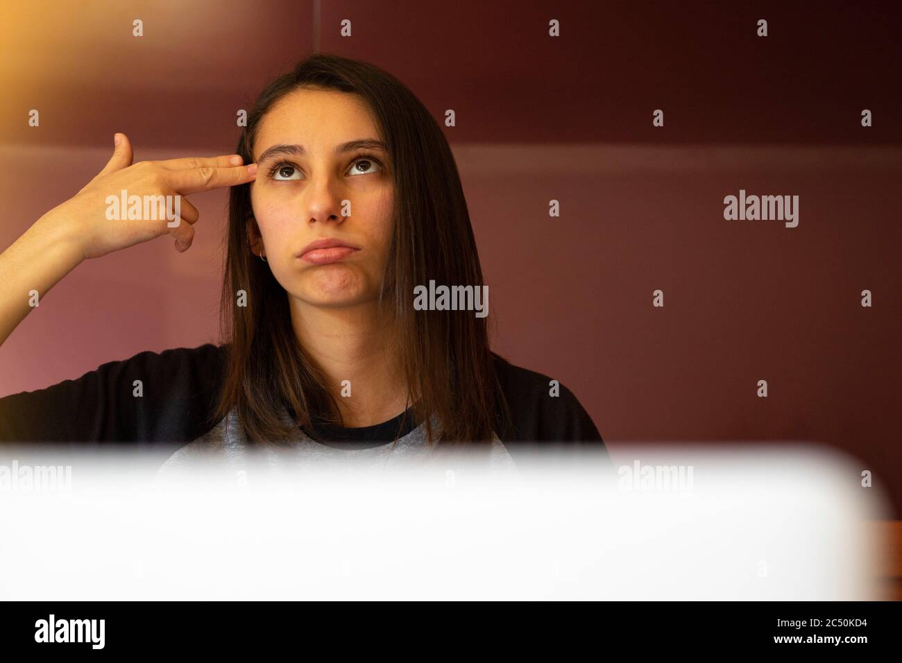 Woman making a gun gesture with her hand. Concept of stress at work. Young woman stressed at work. Stock Photo