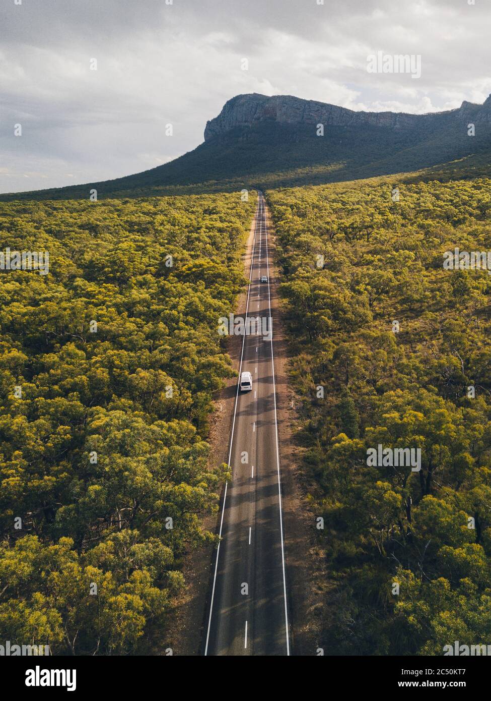 Aerial campervan driving through the endless road towards mountains at