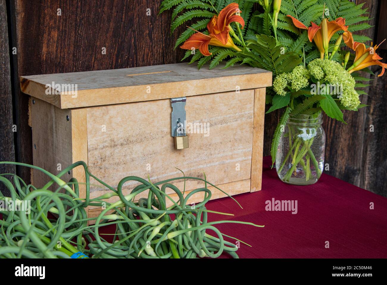 A self-serve farm stand with a wooden money cash box, garlic scapes, honor system, roadside, honesty, buying Stock Photo