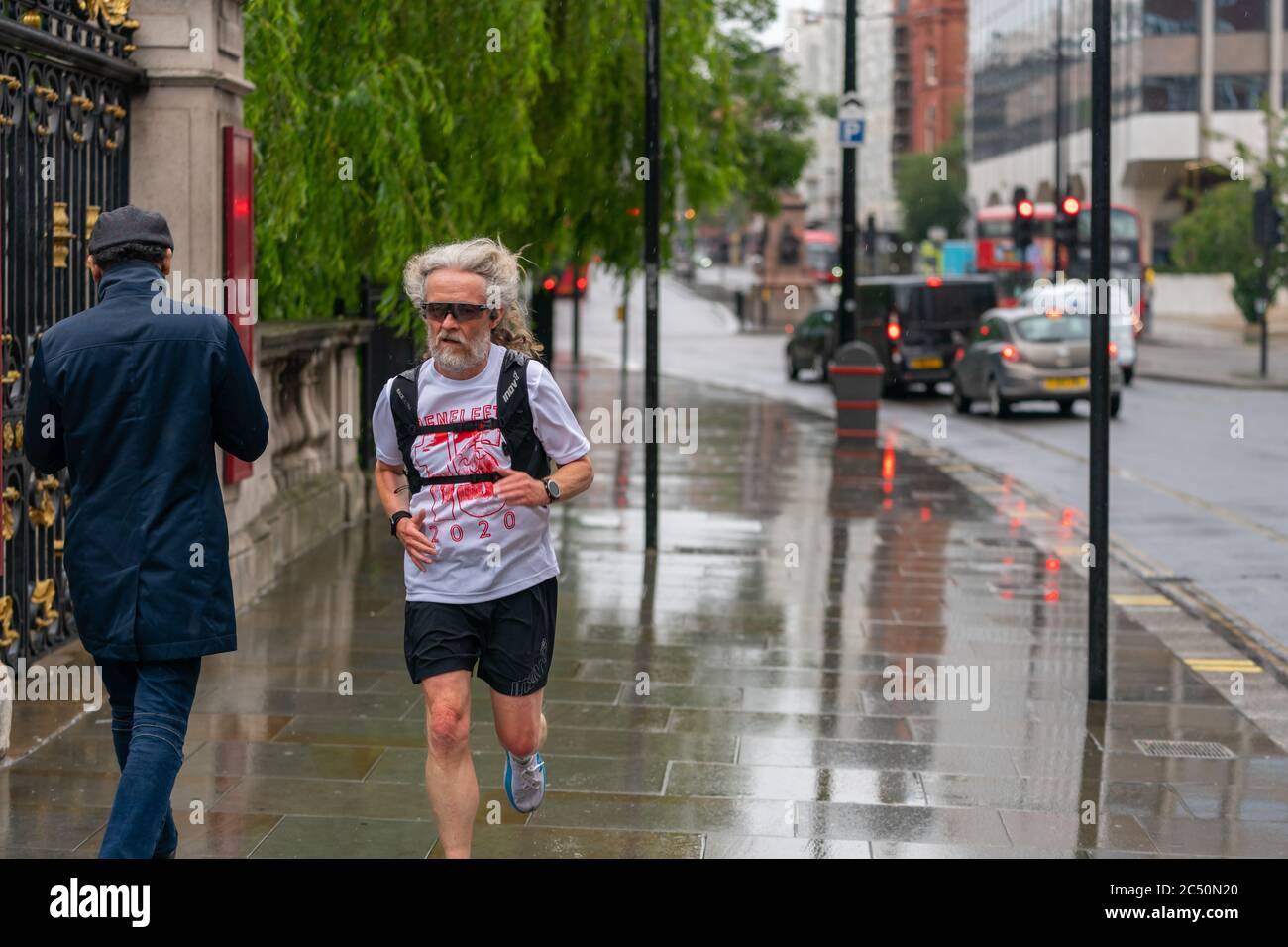 LONDON, ENGLAND - JUNE 10, 2020: Elderly man caught out in the rain jogging on a drizzly day wearing a t-shirt in Holborn, London during the COVID-19 Stock Photo