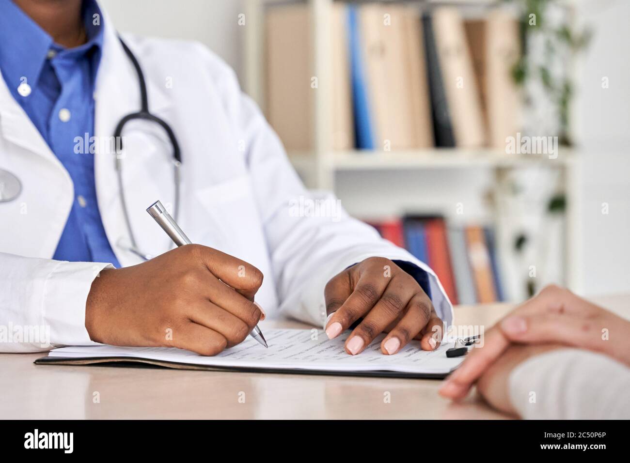 African black doctor consult woman patient filling medical form at appointment. Stock Photo