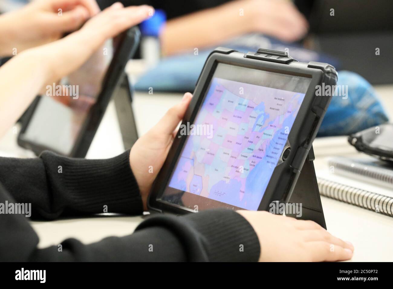 The modern school student in the classroom using a digital device or tablet to work on or research with. Geographical, political theme with colored ma Stock Photo