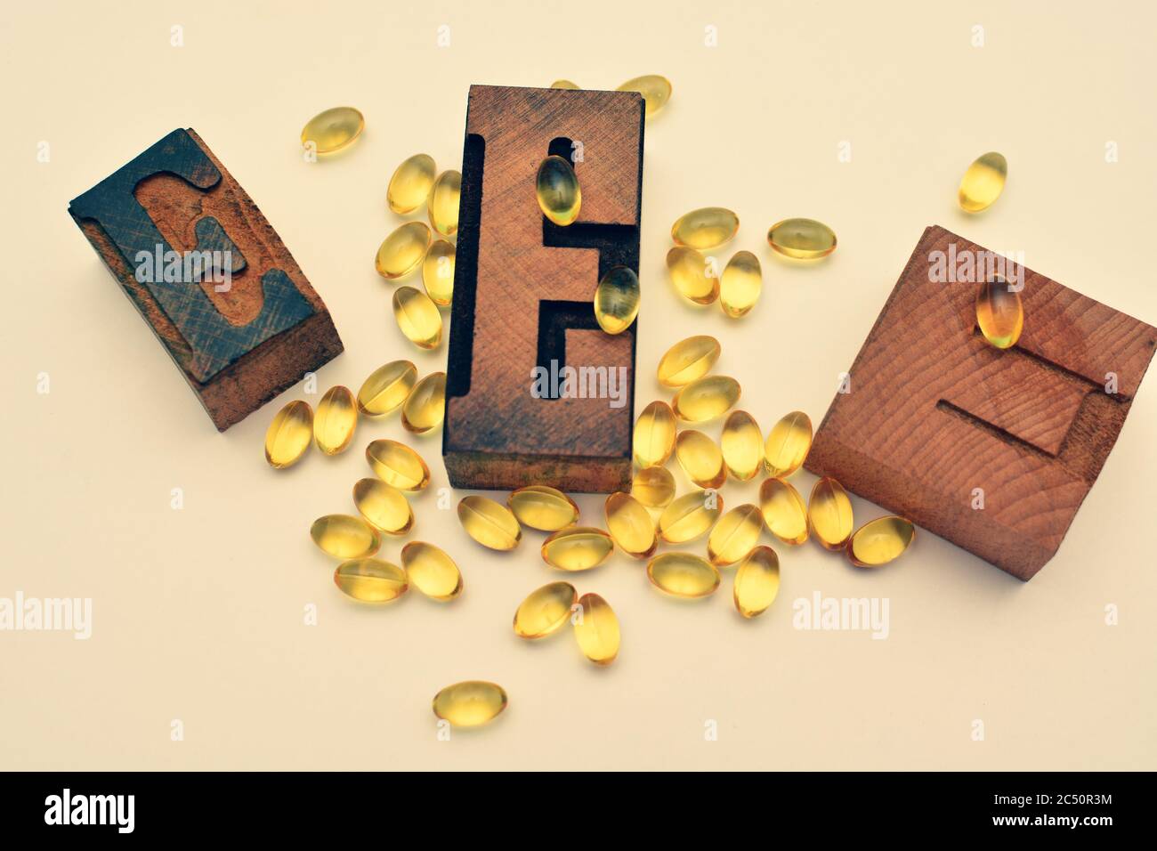 Vitamin E soft gel capsules and wooden typographic letters E. Healthcare and immunity support concept. Stock Photo